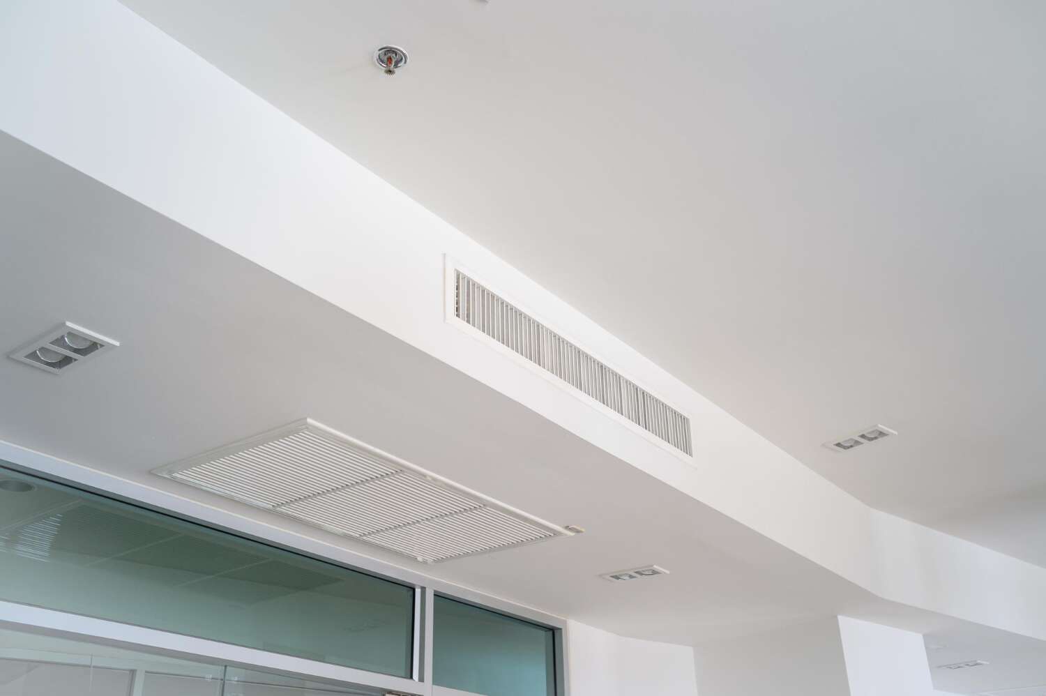 A series of air vents on a rectilinear ceiling.